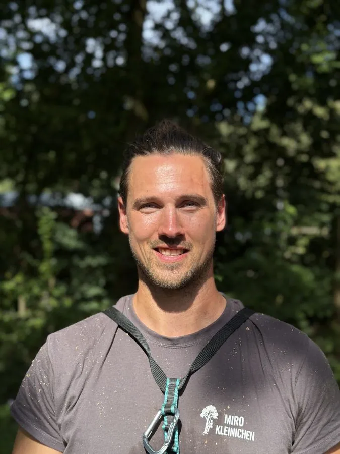 Miro Kleinichen, Baumkontrolleur von Baumpflege Kleinichen, im Firmenshirt vor Bäumen